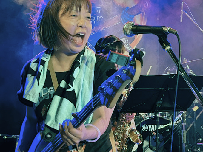 ベースを弾きながら元気よく歌うベースボーカルの女性
