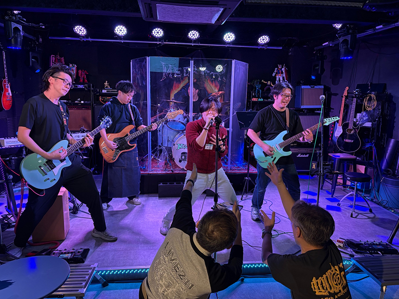 ライブハウスで熱演するバンドとそれを盛り上げる観客