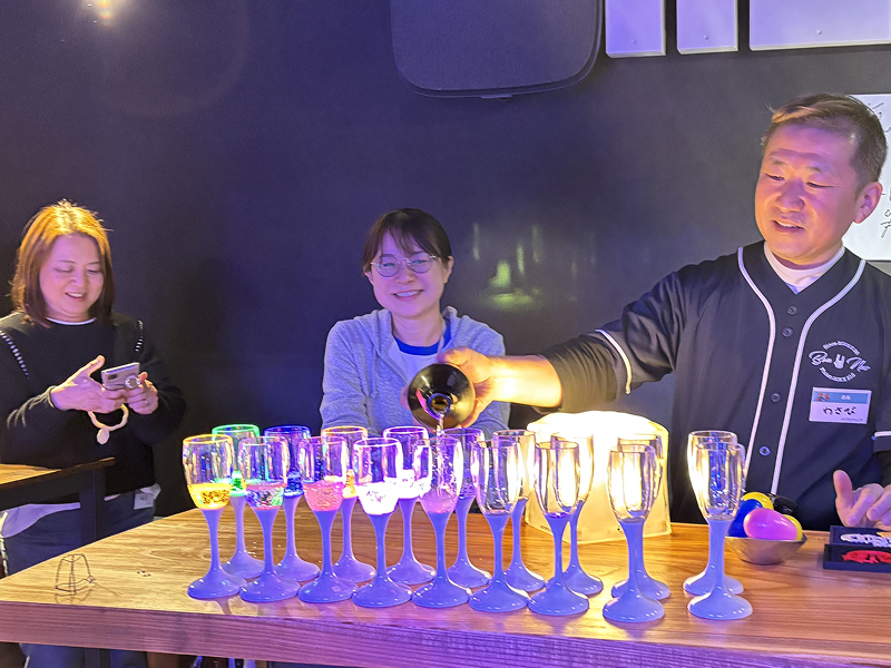 たくさん並べたグラスにシャンパンを注ぐ男性とそれを楽しく見守る女性